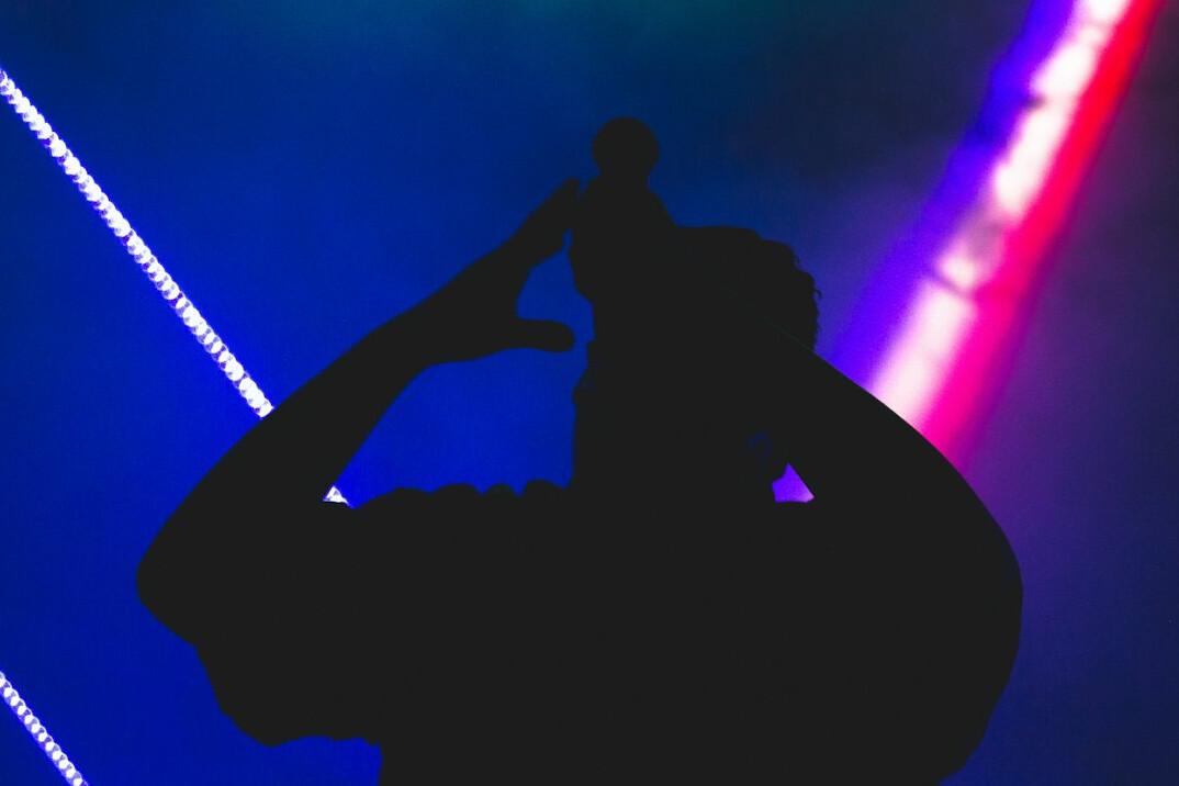 Live concert stage with colorful lights and performer silhouette